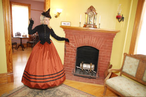 Halloween 2018 Caption This! Photo Contest - orange and black witch at the fireplace