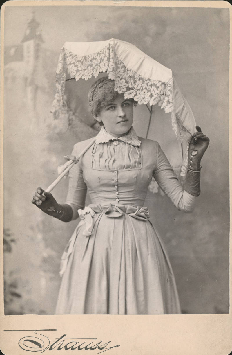 Black and white photo of Polly Pry holding an umbrella and wearig long black gloves